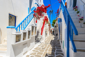 Wall Mural - A view of whitewashed street with blue windows and flowers in beautiful Mykonos town, Cyclades islands, Greece