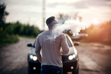 Vaper with beard in sunglasses vaping outdoor, focus on steam