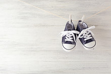 Baby Sport Shoes Hanging On The Clothesline On Light Wooden Background