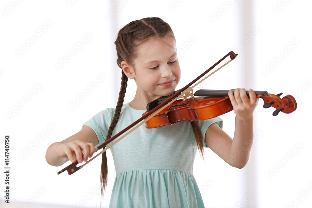 Little girl playing violin on light background