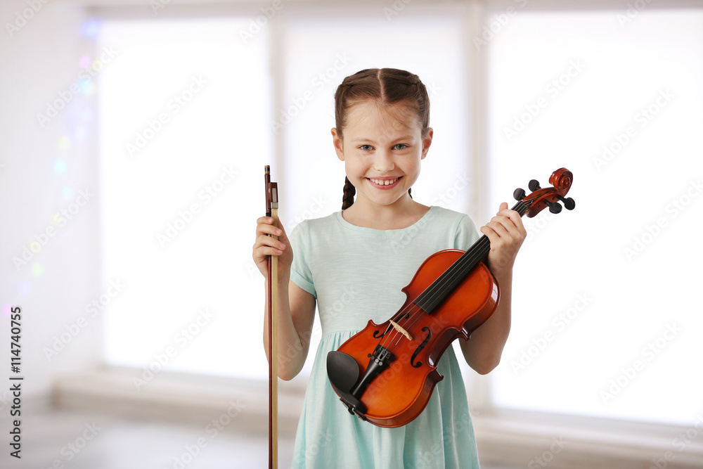 Little girl with violin on light background