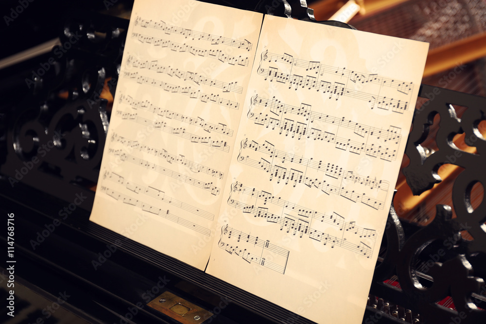 Musical notes on black piano, close up