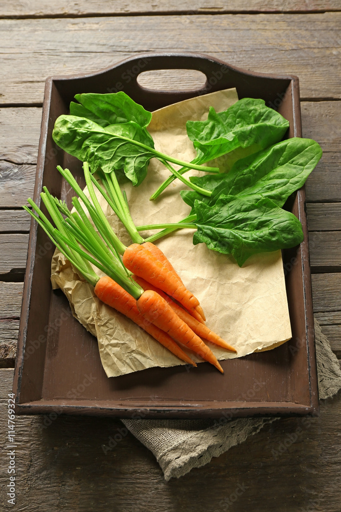 Carrots with sorrel on wooden tray