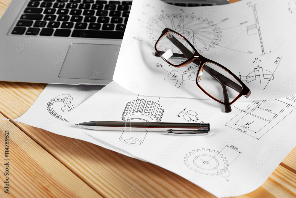 Laptop and engineering drawings on wooden table