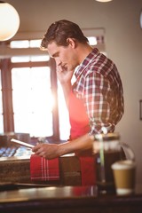 Poster - Waiter talking on mobile phone while using digital tablet