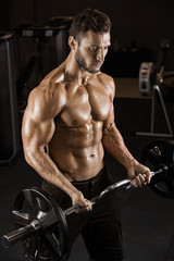  Muscular bodybuilder guy doing exercises with dumbbells in gym