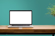 laptop on wooden desk with green wall background