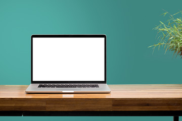 laptop on wooden desk with green wall background