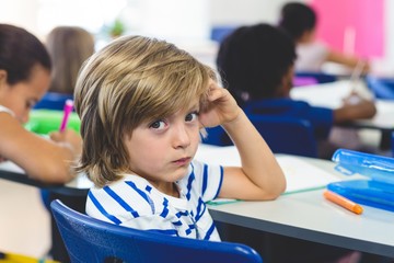 Wall Mural - Serious boy with classmates in classroom