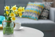 Yellow narcissus on white table in room interior