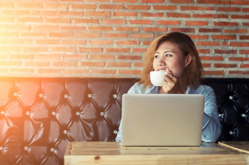 Beautiful young hipster woman drink coffee with her laptop at ca