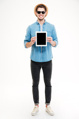 Wall Mural - Smiling handsome young man standing and holding blank screen tablet