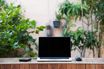 Laptop computer mock up with hard disk on wood texture in garden, middle of frame. Relax from work.