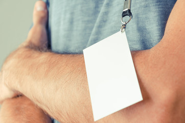 man with arms crossed standing on the side and showing id card