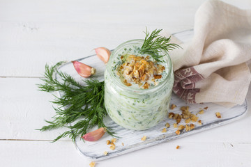 Wall Mural - Traditional Bulgarian sour milk soup, tarator, with yogurt, cucumbers, walnuts and dill in a glass jar, selective focus