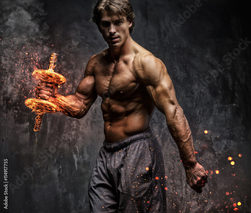 Fotografie, Obraz  A man doing biceps workout with budrning dumbbell..