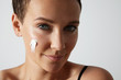 © Anastasia - young woman with a cream on a cheek watching at camera. blue eye