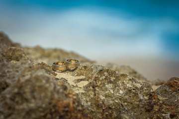 Two wedding rings on the cliff near ocean on the beach