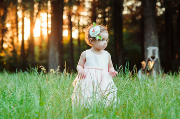 A cute little girl playing in the grass at sunset