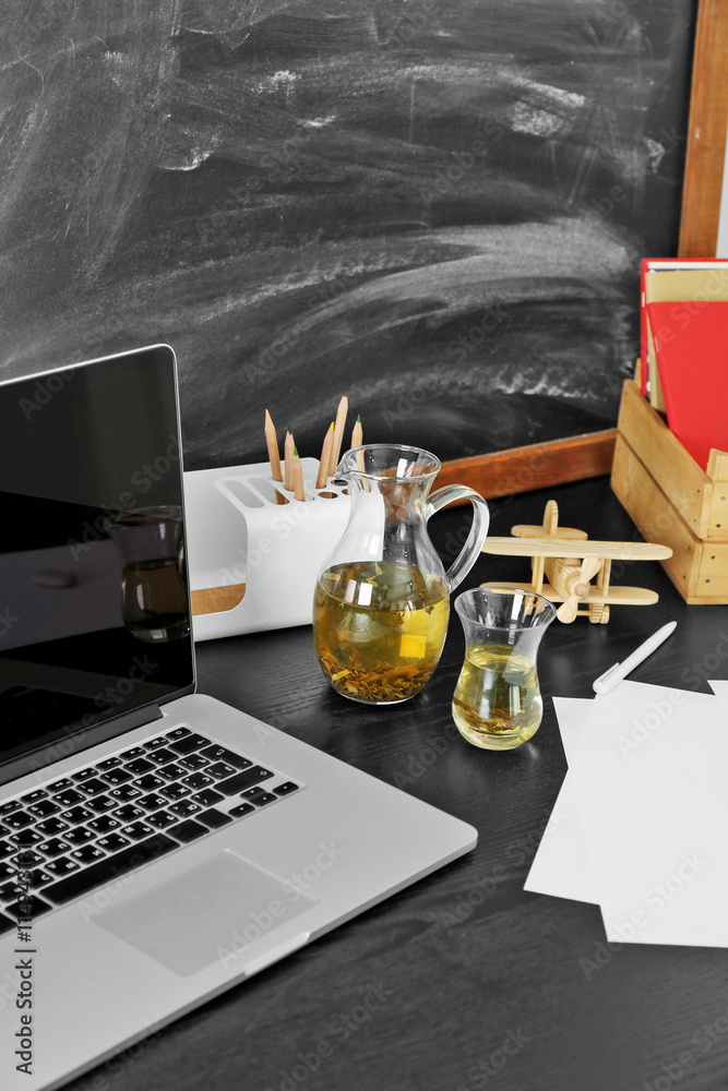 Desktop with notebook and other items on blackboard background