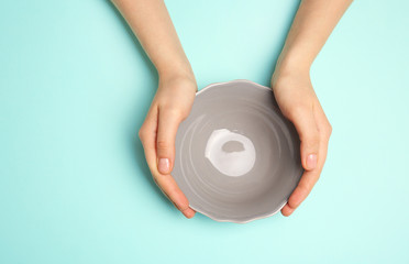 Canvas Print - Female hands and empty bowl on turquoise background