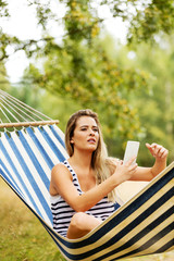 Wall Mural - Young woman on hammock making a selfie