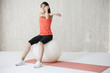 © Monet - Young woman is doing the arm of the stretch sitting on a balance ball