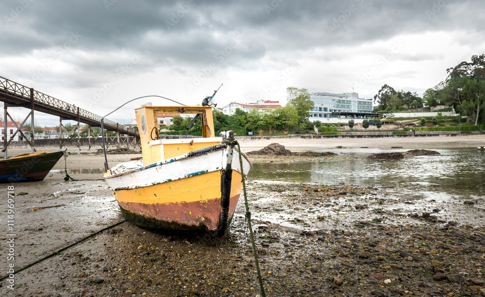 Old fishing boat is moored on beach at low tide. Stock Photo | Adobe Stock