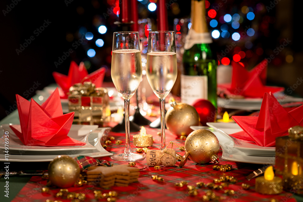 christmas eve party table with champagne flute with red and golden glitter - obrazy, fototapety, plakaty 