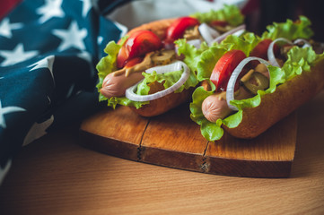 two fresh hot dogs on a wooden Board, glasses with Cola and American flag