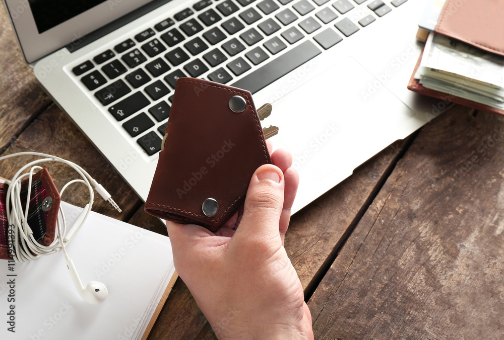 Man hands with keys, laptop and wallet on wooden table