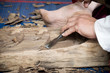 Wood carver man is using a wood chisel to extract.