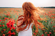 © MZaitsev - Beautiful young red-haired woman in poppy field with flying hair