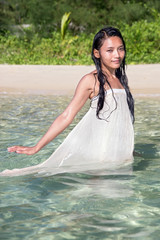 Wall Mural - woman in a white dress walks in the sea