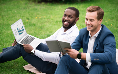 Sticker - Positive smiling colleagues sitting on the grass.