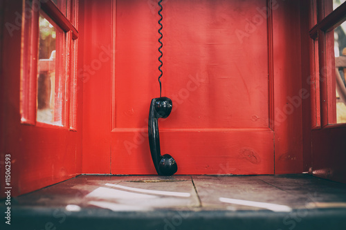 Fotografie, Obraz black handset hanging in a red telephone box
