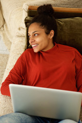 Wall Mural - Attractive lady lying on couch with laptop