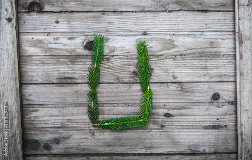 Fototapeta na drzwi i meble Letter U from fir tree branches on aged wooden boards