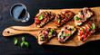 Brushetta set and glass of red wine. Small sandwiches with prosciutto, tomatoes, parmesan cheese, fresh basil, balsamic creme on rustic wooden board
