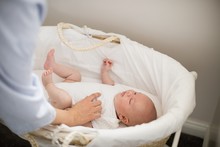 Mother Looking At Baby Sleeping In Moses Basket