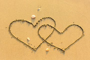 Wall Mural - Two of hearts drawn on a sandy sea beach.
