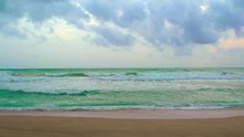 Small, Gentle Waves Break On A Beautiful, Sandy Beach, With A Cloudy Sky And A Flat Horizon Over The Tropical Sea. Video UltraHD