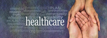 Health Care Worker - Female Hands Gently Cradling Male Hands On A Rustic Dark Stone Background With A Healthcare Word Cloud To The Left