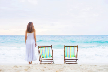 Young woman in a white dress posing on the beach