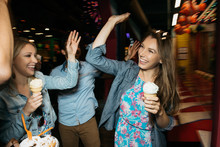 Adult Friends High Fiving Each Other In Amusement Park At Night, Santa Monica, California, USA