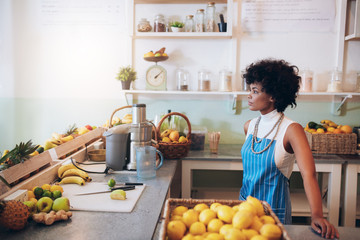 Young female bartender standing at juice bar counter