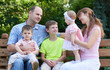 © soleg - happy family portrait on outdoor, group of five people sit on wooden bench in city park, summer season, child and parent