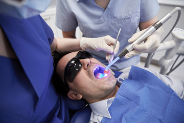 Wall Mural - dentists treating male patient teeth at clinic