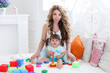 © GTeam - A young mother,blond with curly hair,was playing with his little daughter in a logical educational games,pyramid and collect the colored blocks,the daughter is a brunette with two tails on the head