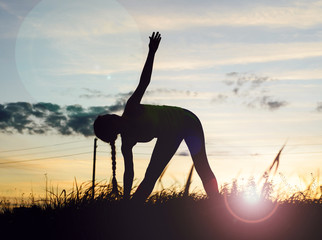 Silhouette young woman practicing yoga at backyard